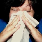 A woman blowing her nose into a tissue