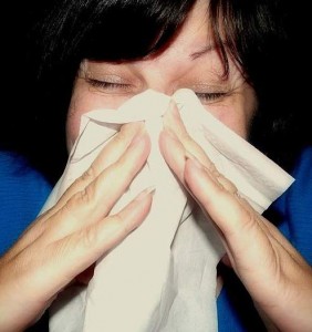 A woman blowing her nose into a tissue