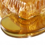 A close up of honey dripping from honeycomb