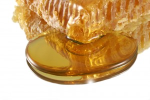 A close up of honey dripping from honeycomb