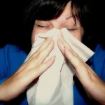 Photo of a woman sneezing into a hankie
