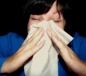 Photo of a woman sneezing into a hankie