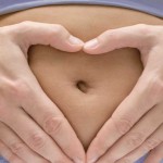 Photo of a woman forming a heart with her hands on her belly