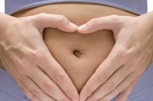 Photo of a woman forming a heart with her hands on her belly