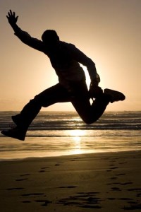 Photo of a man jumping for joy at eth seaside