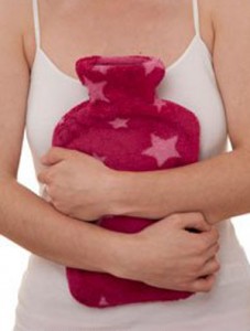Photo of a woman's hands holdilng a hot water bottle to her abdomen