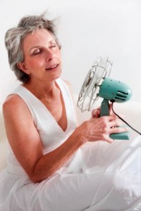 Photo of an older woman cooling herself off with a fan