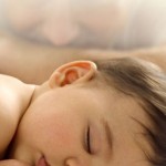 Photo of a baby boy sleeping with father in the background