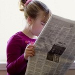 Photo of a child reading a newspaper