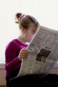 Photo of a child reading a newspaper