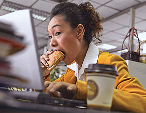 Photo of a woman eating at her desk