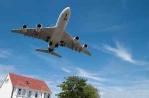 Photo of a jet aircraft flying over a house