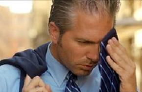 Photo of a sweating man wiping his face with his tie