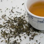 Photo of a cup of green tea and dried tea leaves