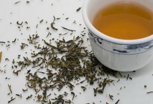 Photo of a cup of green tea and dried tea leaves