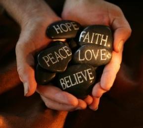 Photo of hands holding stones with spiritual messages written on them