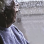 Photo of an older woman looking out of a window