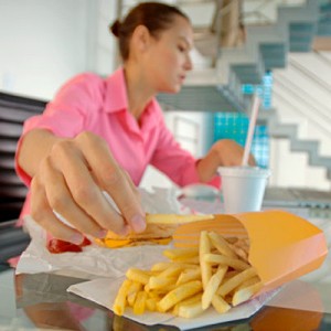 Photo of a stressed woman eating junk food
