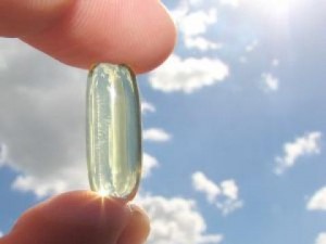 Photo of fingers holding a vitamin D capsule