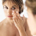 photo of a woman examining her skin in the mirror