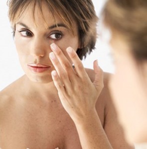 photo of a woman examining her skin in the mirror