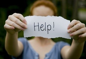 Depressed woman holding up a 'help' sign